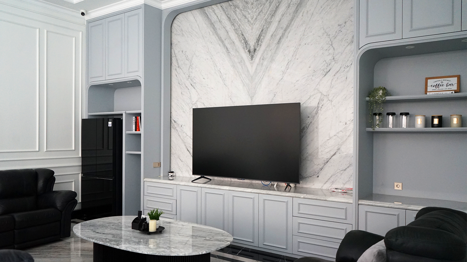 Living room lantai dua rumah Mr. H dengan backdrop televisi bookmatch marmer putih dan kabinet bernada abu